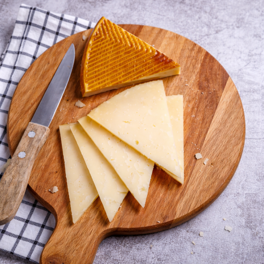 Kačkavalj od parenog testa isečen na trouglove na drvenoj dasci, sa nožem i rustičnom kuhinjskom pozadinom